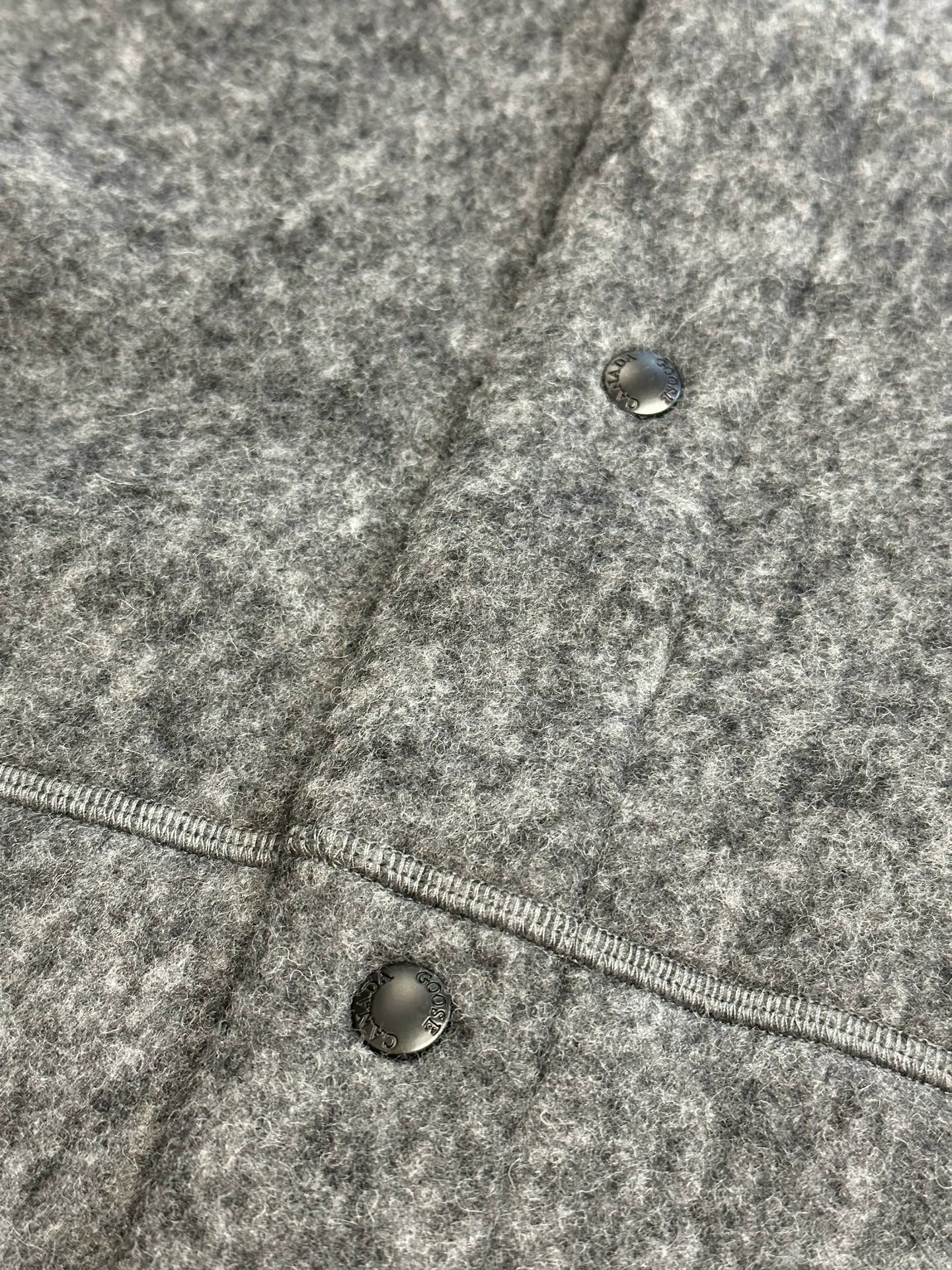 P770 Canada Goose Fleece Badge Button Jacket The main fabric of this jacket is light gray wool blend fabric to improve the fabric's wear resistance, wrinkle resistance and warmth. Wool provides good warmth and a natural feel, while blended fibers enhance the fabric's practicality and durability.  The cutting process needs to ensure that the texture and color of the fabric are evenly distributed, especially with this light gray tone, to avoid chromatic aberrations. The stretchability of wool-blend fabrics needs to be taken into consideration when cutting pieces to ensure dimensional stability of the finished garment.  Use a sewing needle and thread suitable for wool-blend fabrics to avoid damage to the fabric during sewing. The sewing stitches are even and firm to prevent thread stripping.  The temperature needs to be controlled during ironing to avoid high temperature damage to the fabric while keeping the fabric smooth and crisp. The front and back body parts, sleeves and other main parts are stitched with flat seams to ensure a smooth silhouette. Align the fabric texture at the splices to keep the look neat.  The white circular armband on the left arm is an important part of the brand identity and is finely sewn to ensure it is strong and flat.  size：s m l xl